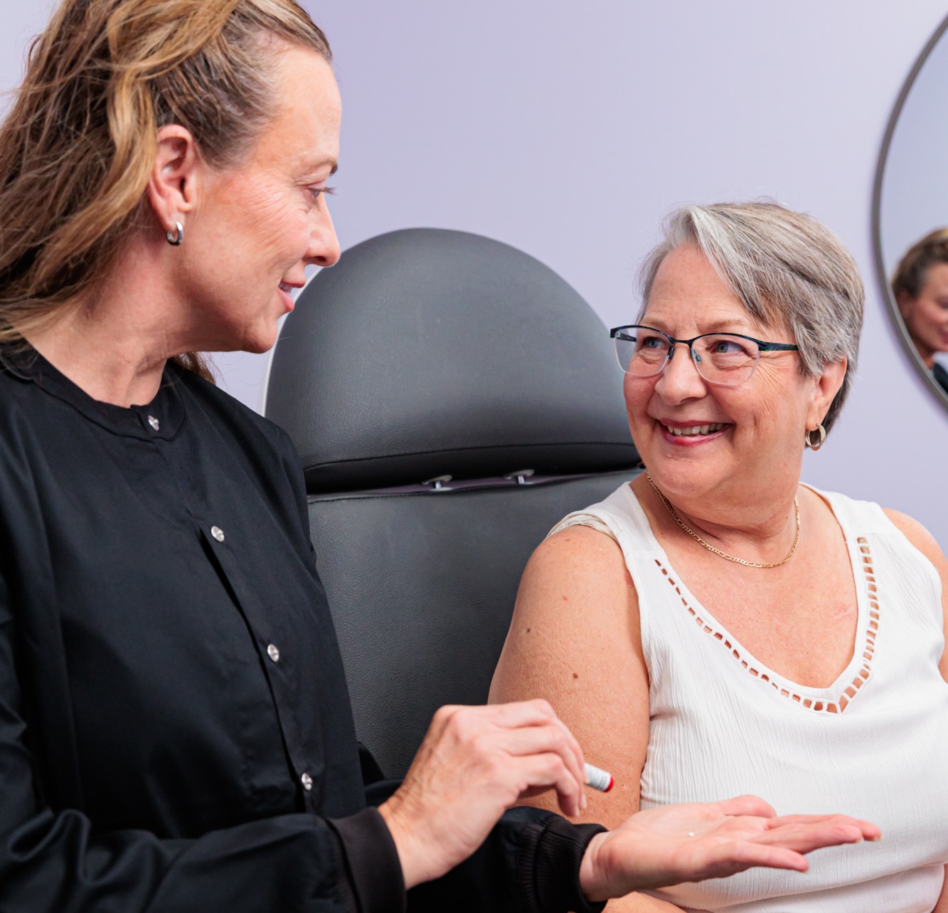 A mature female patient smiles at a provider as the provider shows her the pellets used for bioidentical HRT in Portage, MI.